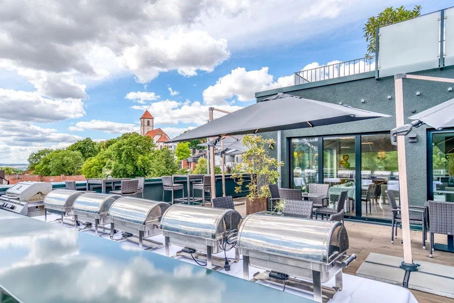 Dachterrasse des Hotel Beckmann Göttingen mit Sitzplätzen und Blick auf die Nikolausberger Klosterkirche.