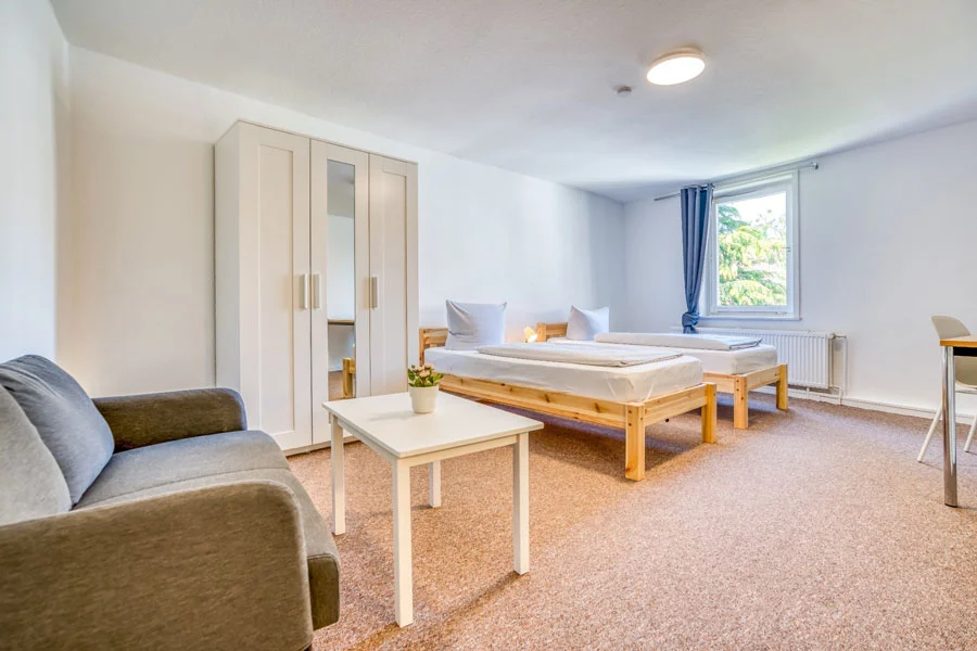 Geräumiges Doppelapartment im Hotel Beckmann Göttingen mit zwei Betten, Sitzbereich und Schreibtisch.