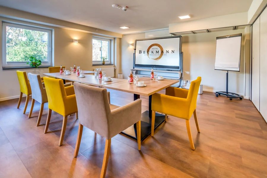 Emmy-Noether-Raum im Hotel Beckmann Göttingen mit Präsentationsbildschirm, Flipchart und U-förmiger Bestuhlung.